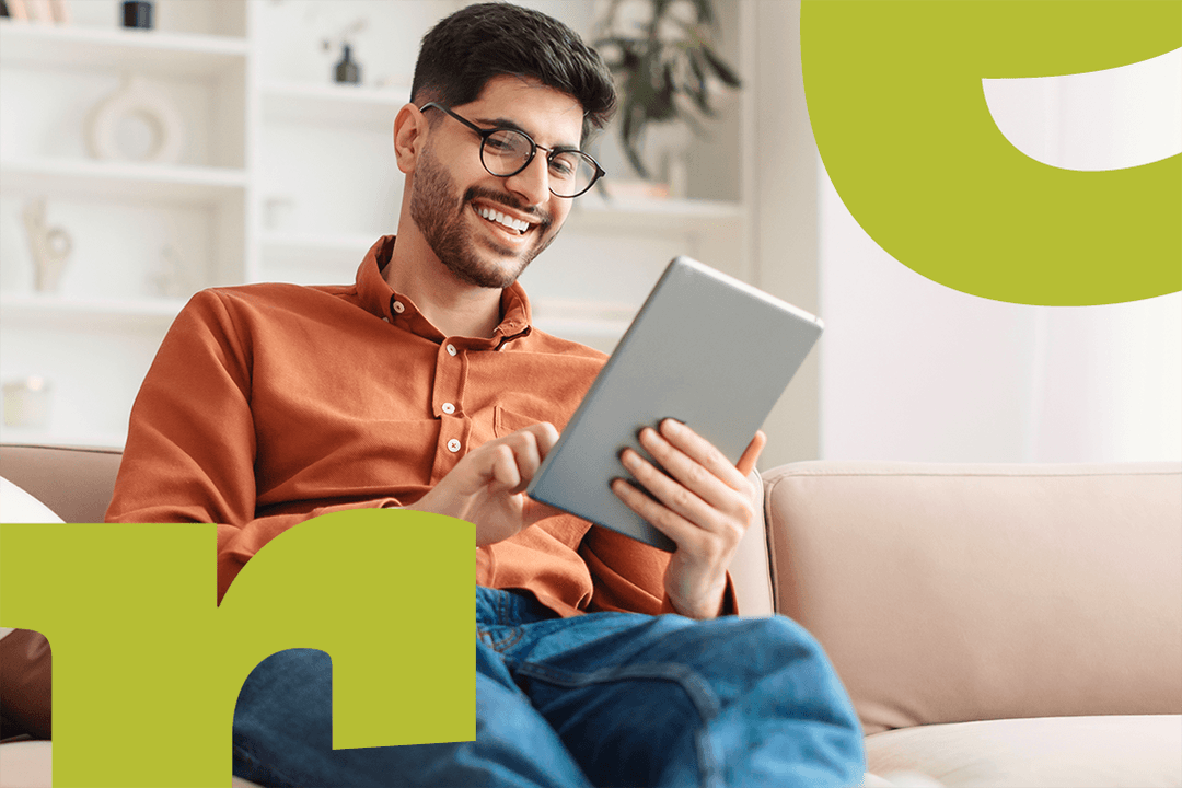 A smiling man sitting with a tablet in his hands.